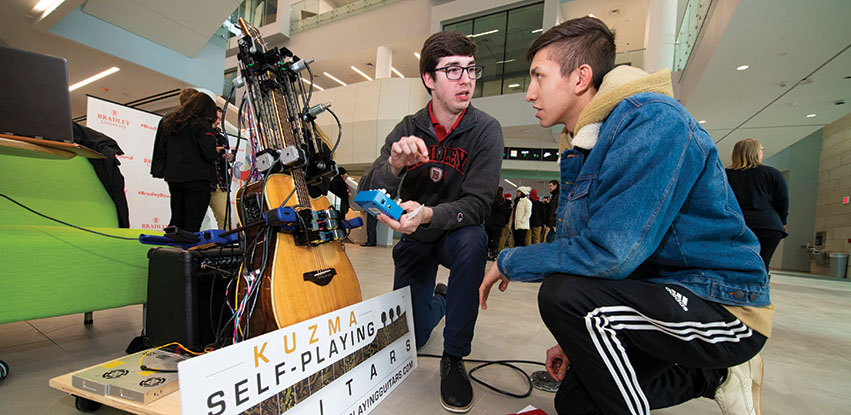 Inventor Michael Kuzma demonstrates his Kuzma Self-Playing Guitar system at an event at Bradley University.