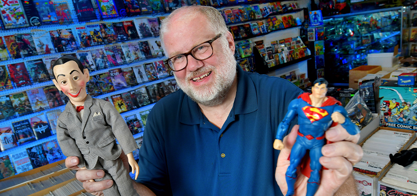 A man in a comic store holding action figures