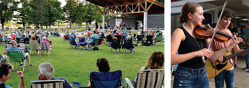 A crowd sitting in lawnchairs listening to live music at a pavilion, a woman playing a violin and a man playing a guitar.