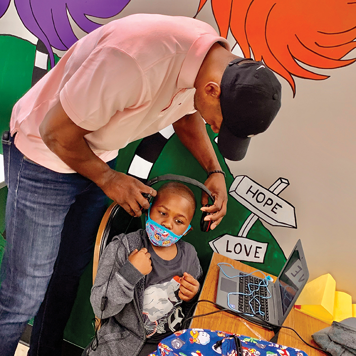 Peoria Friendship House CEO Marcellus Sommerville assists a student with e-learning through their STEAMS Academy program.