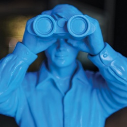Photo of a blue plastic toy man looking thru binoculars