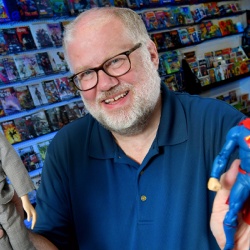 A man in a comic store holding action figures