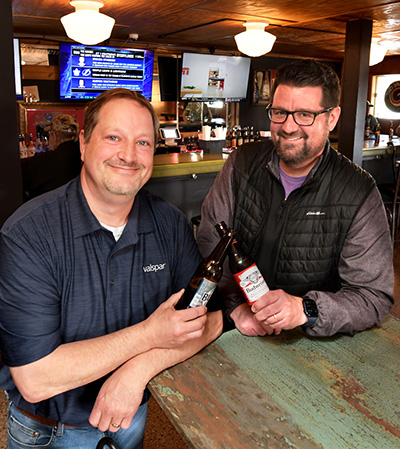 Men in a bar toasting beer bottles