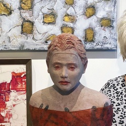 Artist Billie Howd at Exhibit A Gallery with "Survivor" sculpture and abstract paintings "Fracture" (top) and "Warm Winds" (left). 